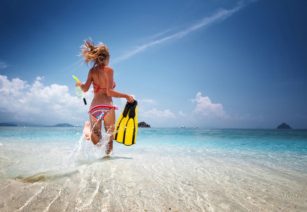 Frau im Bikini und Schnorchel rennt voller Freude ins Meer