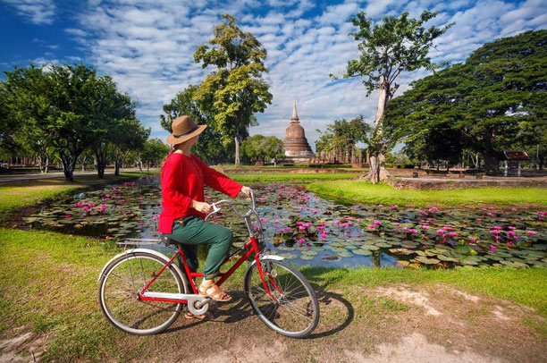 Frau mit Fahrrad vor den Ruinen von Ayutthaya