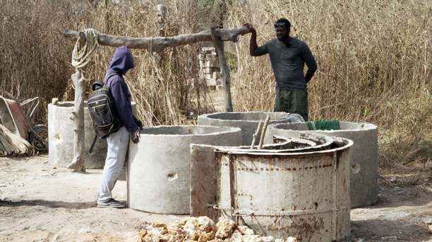 Api im Gespräch mit einem Brunnenbauer in Cap Skirring, Senegal. Thema ihrer Diskussion: Lohnt es sich nur aus wirtschaftlichen Gesichtspunkten zu versuchen nach Europa  zu gelangen oder liegt die Zukunft und ein erfüllteres Leben nicht im eigenen Land?