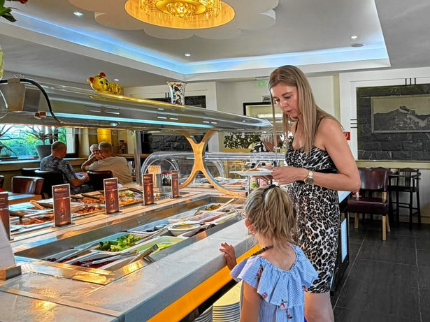 Mutter und Kind wählen gemeinsam Speisen am Buffet aus