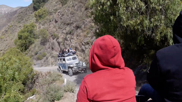 2 jeeps trying to pass each other - people sitting on the roof of the car