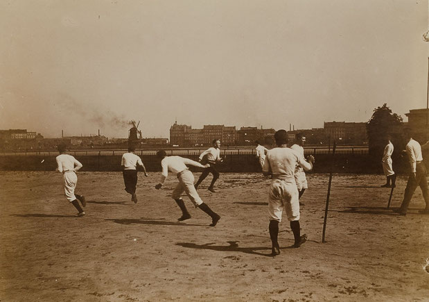 Schlagballspiel auf dem Heiligengeistfeld in den 1900er Jahren. Im Hintergrund ist die Feldstraße zu sehen mit der markanten 1938 angerissenenen Windmühle (Foto: Heinrich oder Johann Hamann; Quelle: Museum für Kunst und Gewerbe, Hamburg, P1994.1046)