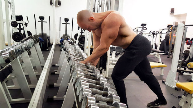 Professional personal trainer in Monaco performing strength training with dumbbells in a high-end gym, offering tailored fitness programs