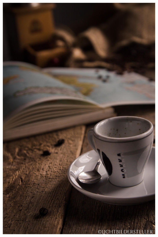 Tasse Espresso mit Atlas und Kaffeemühle im Hintergrund