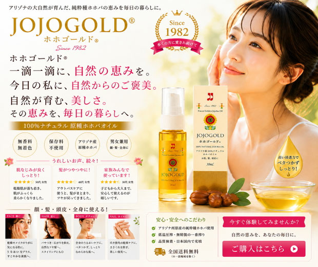 ホホゴールド®のプロモーション画像。アリゾナ州原産の100％ナチュラル原種ホホバオイル「ホホゴールド®」のボトルと化粧箱、ホホバの実、オイルを入れたガラス容器を配置。右側には頬に手を添えた女性モデルが描かれ、「一滴一滴に、自然の恵みを。今日の私に、自然からのご褒美。」のキャッチコピーや、顔・髪・頭皮・全身に使えること、無香料・無着色などの特長、Since 1982のロゴがデザインされた上品なブランドビジュアル。