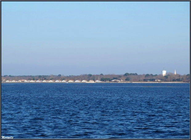 Le port d'Arès et ses cabanes ostréicoles alignées, le château d'eau et le clocher de l'église St Vincent de Paul (photo prise depuis Claouey), Bassin d'Arcachon 