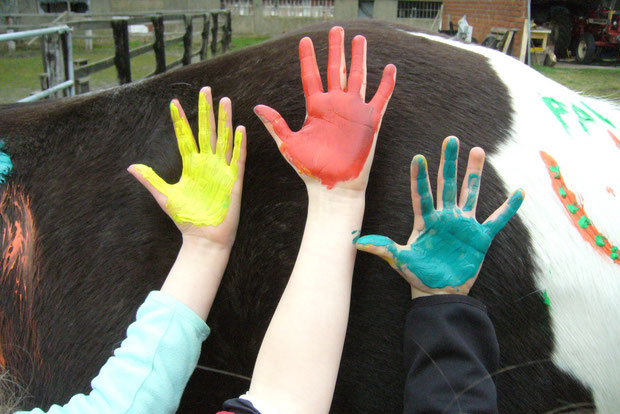 Bunte Kinderhände bemalen Pferd