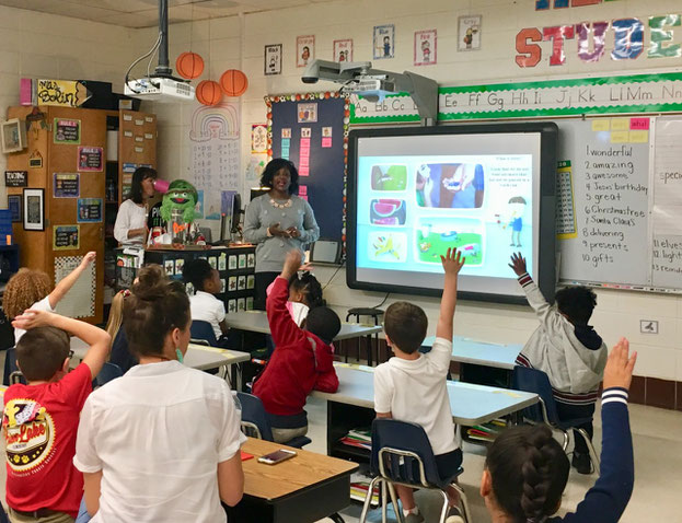 Children at school learning about litter and raising their hands to ask questions