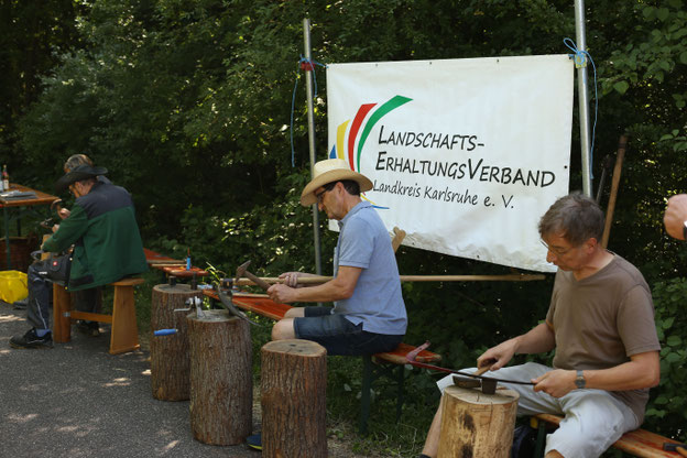 Teilnehmer des Mäh- und Dengelkurses schärfen ihre Sensen und lernen den richtigen Umgang damit. Foto LEV
