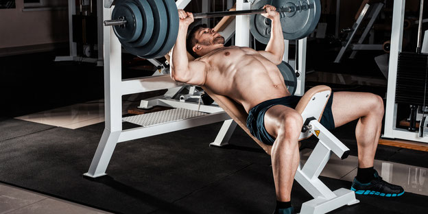 muskulöser Athlet stemmt schwere Gewichte in einem Fitnessstudio