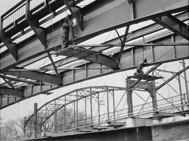 View showing welders at work on both the north and south girders, with the old bridge in the background, looking northwest , around 10 May 1949