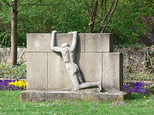 Mann zieht sich an Mauer hoch. Denkmal zum Leid an der Mauer