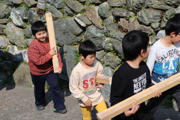 盤木を運ぶ少年たち