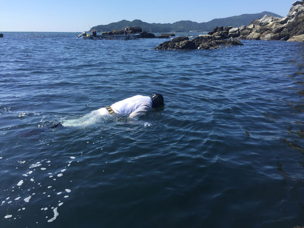 海に浮く白装束の男性