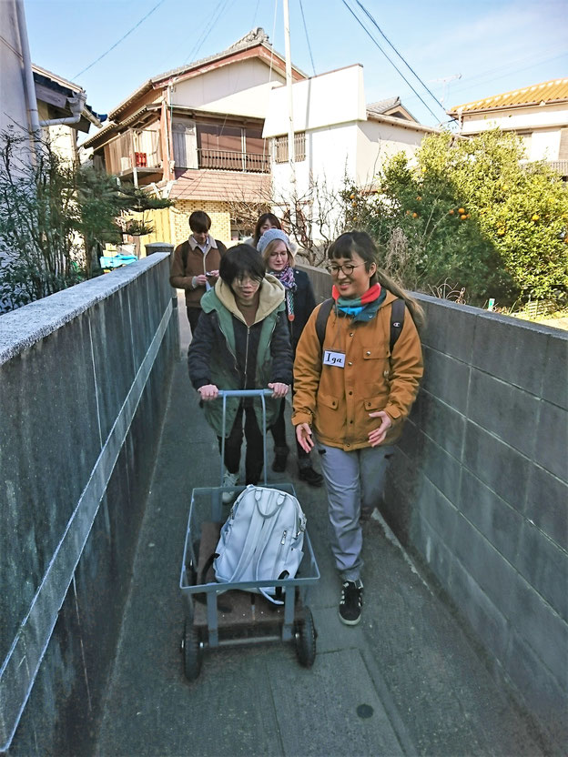 じんじろ車を押しながら路地を歩くお客さんといがちゃん