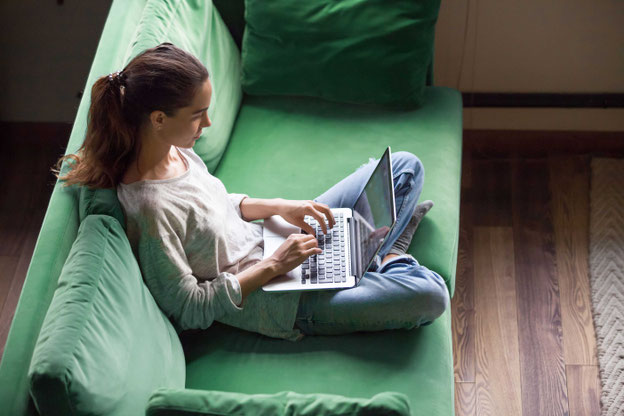 Mädchen mit Laptop auf grünem Sofa