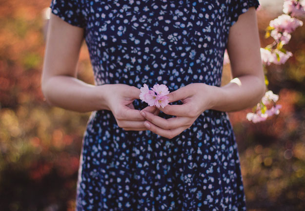 Bild von einer Frau die eine Blume vor ihren Bauch hält