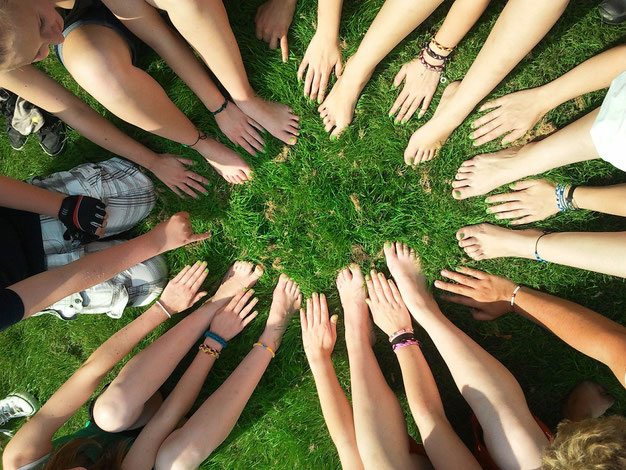 Jugendliche sitzen in einem Kreis und strecken ihre Hände in die Mitte. Bild von Henning Westerkamp auf Pixabay.