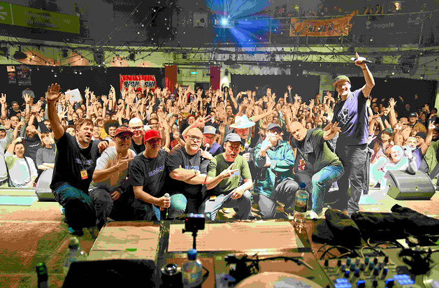 Gruppenfoto der Hip‑Hop‑Crew Blitz Mob auf der Bühne des zakk Düsseldorf beim Lieblingsplatte Festival 2025, mit jubelndem Publikum im Hintergrund.