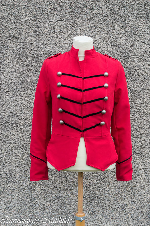 Veste en gabardine extensible rouge doublée de satin de coton noir et décorée de velours et de boutons en métal.