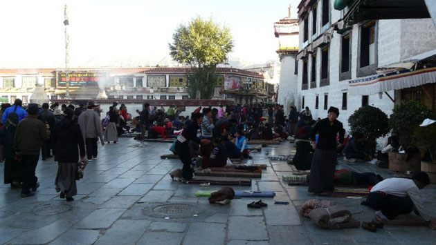 Sur la place du Barkhor, les pelerins se prosternent devant le temple