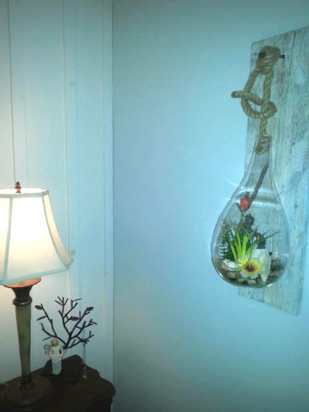 Cottage style bedroom suited this raindrop terrarium hanging from a rustic rope and spiked into a piece of barn board creating unique wall decor.