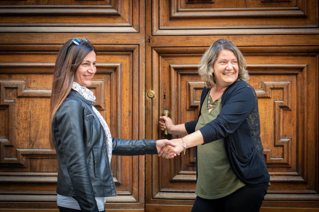due donne che si stingono la mano davantio a un portone