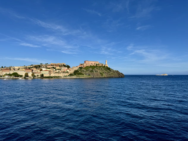Portoferraiso taucht hinter einer Landzunge mit dem Forte Stella und seinem Leuchtturm auf. 