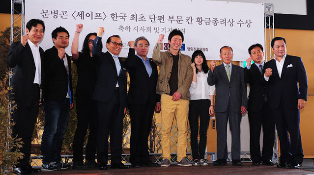 Ministro de Cultura, Deportes y Turismo Yoo Jin-ryong (junto al director) celebran el premio de la Palma de Oro-Rueda de Prensa (photo: Yonhap News).