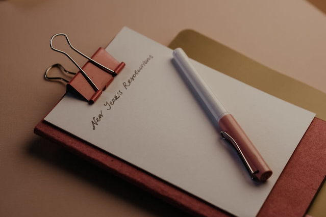 A pen and a notepad with “New Year’s Resolutions” written on it