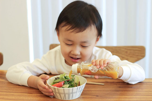 食べる玉ねぎドレッシングを自分でサラダにかける子ども