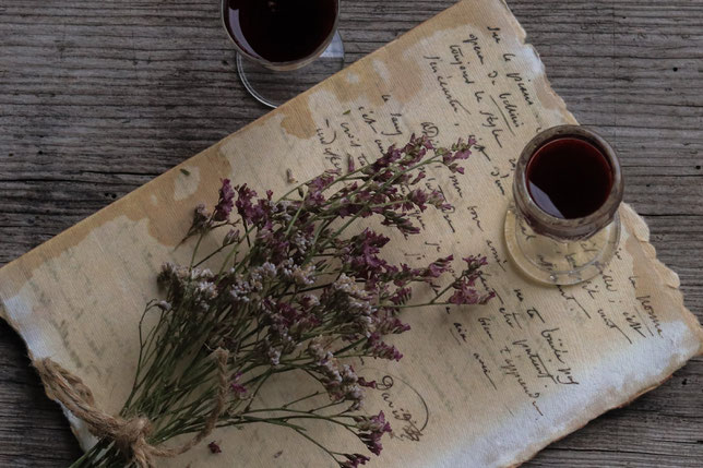 Aronialikör in einem Glas und getrocknete Blumen