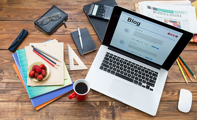 Schreibtisch mit Utensilien für das Bloggen: Laptop, Notizbuch, Stiftes