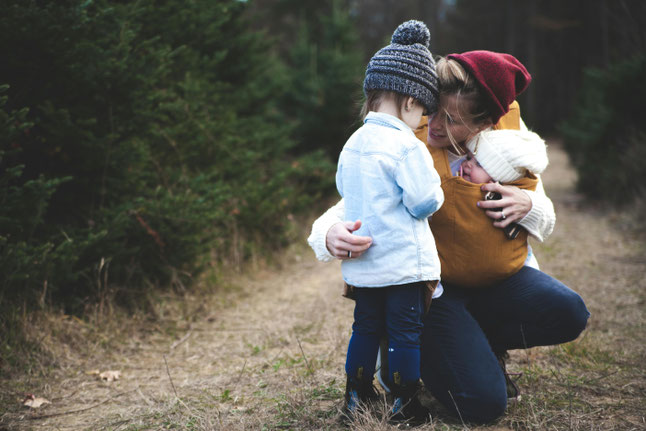 Mutter mit zwei Kindern im auf Augenhöhe mit dem Kleinkind