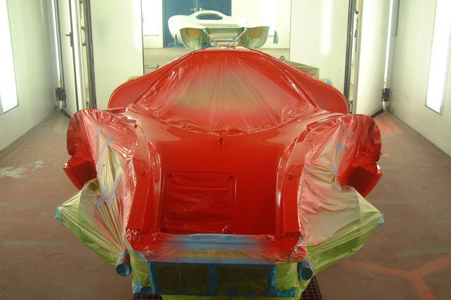 Finish-painted car with front and tail waiting for their red coat in the background