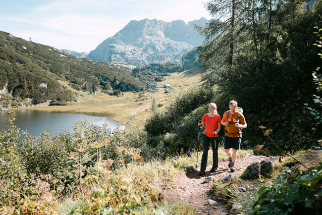 Wanderer auf Bergpfad mit Blick auf einen alpinen Bergsee und die Berglandschaft rund um den Traunsee