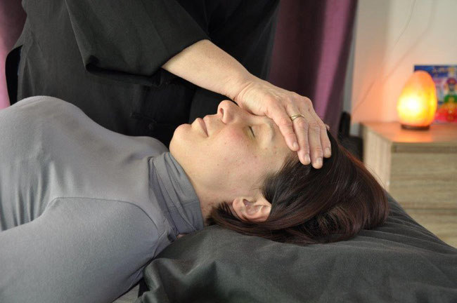 Femme allongée sur le dos  recevant un soin de magnétisme. main posée sur son front