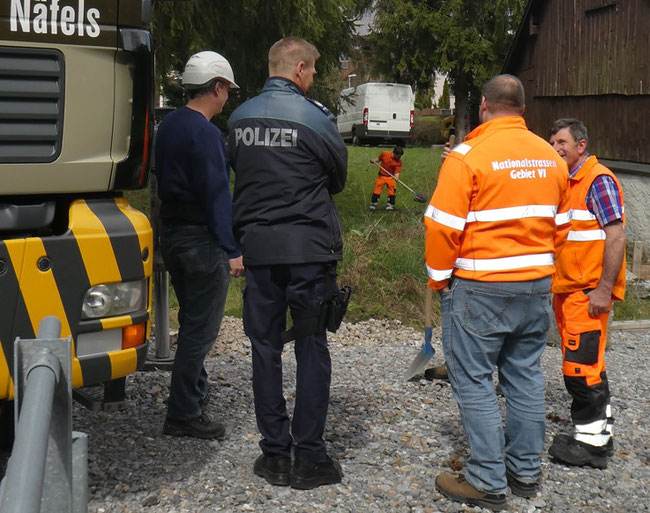 Abräumen unter Polizeischutz. Sogar ein Mann von "Nationalstrassen Gebiet VI", Zweiter von rechts, ist anwesend. Im Hintergrund ein Mitarbeiter des Bauamts beim Räumen. (Foto: Kurt Philipp Hauser)