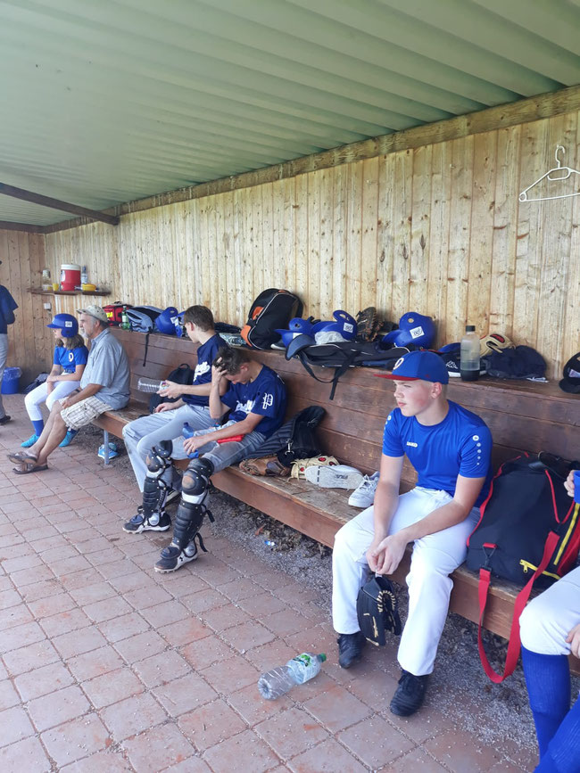 Abgekämpft zwischen den Einsätzen. Jeder sucht den Schatten im Dugout (Spielerbank). Besonders schweißtreibend sind die Catcher mit ihrer intensiven Schutzausrüstung unterwegs. – Foto: Mariusz Slomka