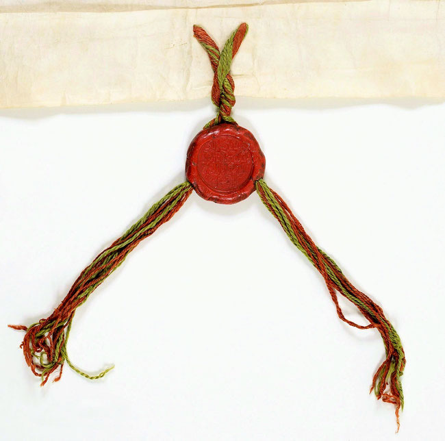 Sceau du bey de Tunis sur lacs de soie rouge et verte. Ce sceau n'est pas figuré il est couvert de texte en arabe. Il mesure 5,5 cm de diamètre.