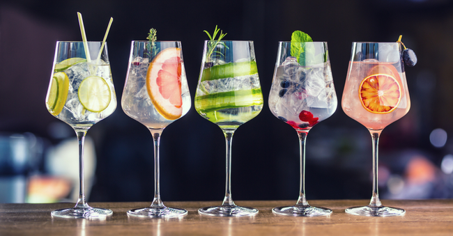 Fünf farbenfrohe Gin Tonic Gläser auf einer Bar