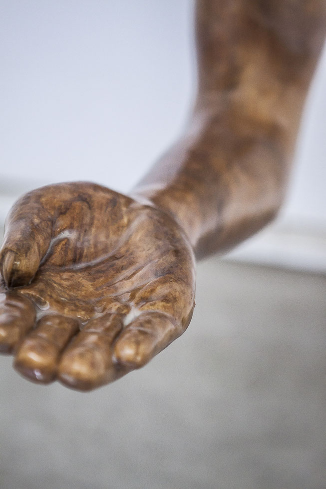 Eine braune, scheinbar feuchte Hand kommt aus der Wand. Slip ist eine figurative Abeit von Oliver Braig. Der Konzeptkünstler soiel hier mit unseren Emotionen. Der Arm ist gestreckt und die Handfläche zeigt nach oben. Was will die Hand vom Betrachter? 