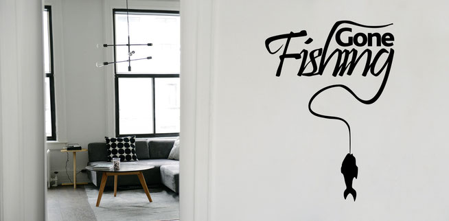 Gone Fishing text quote, black on a white wall. A fish has been caught on the end of the 'g' making a fishing rod.