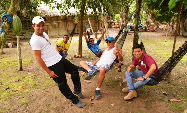 Jóvenes conversan recostados en hamacas bajo el follaje de cacaoteros en el Balneario Cabaña de Toto. Chone, Ecuador.