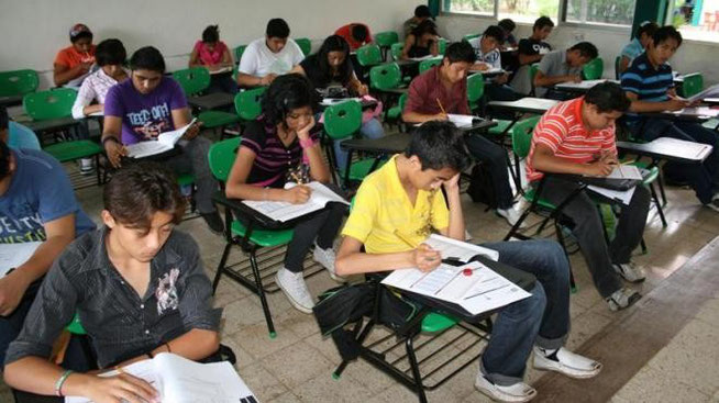 Estudiantes de bachillerato resolviendo un examen dentro del aula de clases.