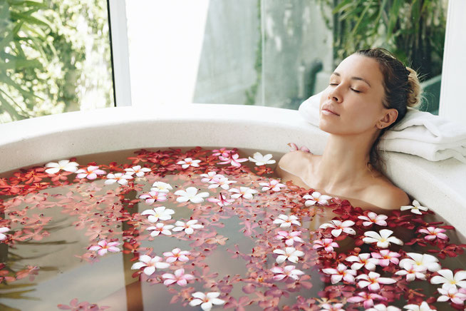 Une jeune femme méditant dans un spa rempli de pétales de rose