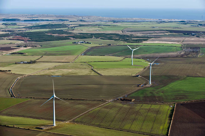 Aerial photo of the 3 Hill of Fiddes wind turbines, showing fields and in the distance the North Sea