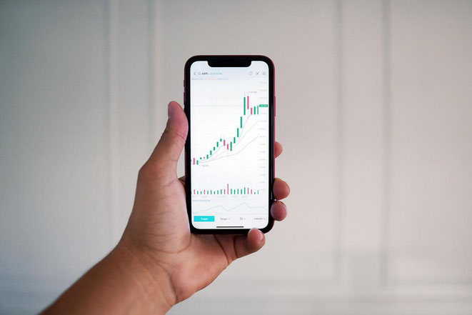 freaky finance, Investments, App-Vergleich, eine Hand hält ein Mobiltelefon, Candlesticks, Chart