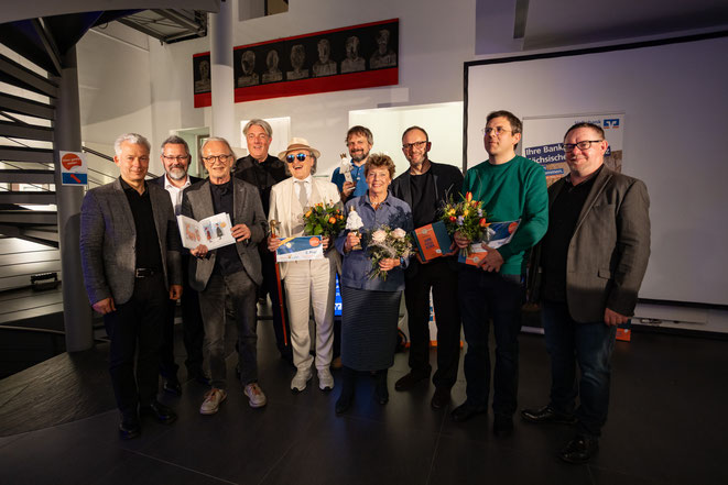 Sechs Sieger, die Bankchefs und zwei Galeristen freuen sich in der Volksbank Pirna über eine wundervolle Karikaturenausstellung mit rund 90 Werken von fast 60 Künstlerinnen und Künstlern aus ganz Deutschland. Motto: "Schön flüssig bleiben!"