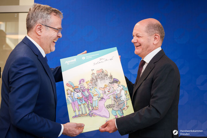 Bundeskanzler Scholz erhält 2023 das von Karikaturistin Barbara Henniger signierte Siegerbild "Damenwahl" aus den Händen des Handwerkskammer-Präsidenten Jörg Dittrich. Die Galerie Komische Meister kuratiert die Schau im njumii Foto: A. Wirsig/HWK Dresden 